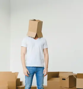 Hombre con una caja en la cabeza rodeado de cajas