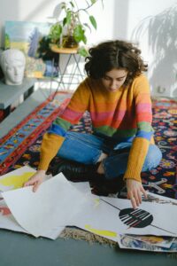 Chica en casa mirando distintos dibujos, sentada en el suelo.
