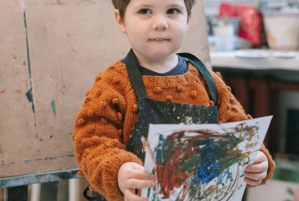 Niño sosteniendo un dibujo que ha hecho con pintura de tipo oleo