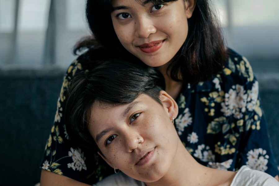 Dos mujeres, una abrazando a la otra por la espalda