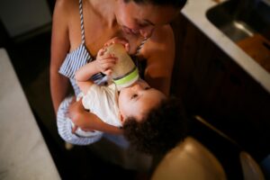 Una mujer sosteniendo a un niño pequeño que bebé de su biberón