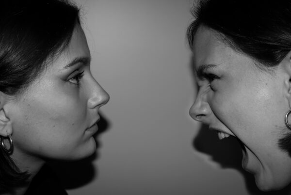 Dos mujeres enfrentadas, es posible que sean la misma mujer cara a cara, una esta neutra la otra está gritando visiblemente.